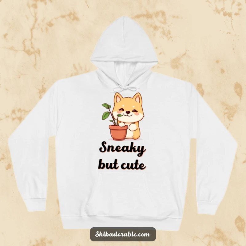 Funny Shiba Inu hoodie showcasing a dog with a wide, mischievous grin, peeking out from behind a green potted plant, looking playful.